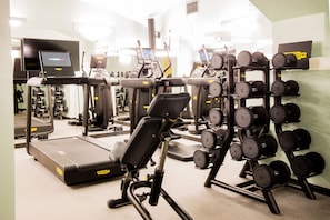 A gym with treadmills, elliptical machines, and a rack of dumbbells.