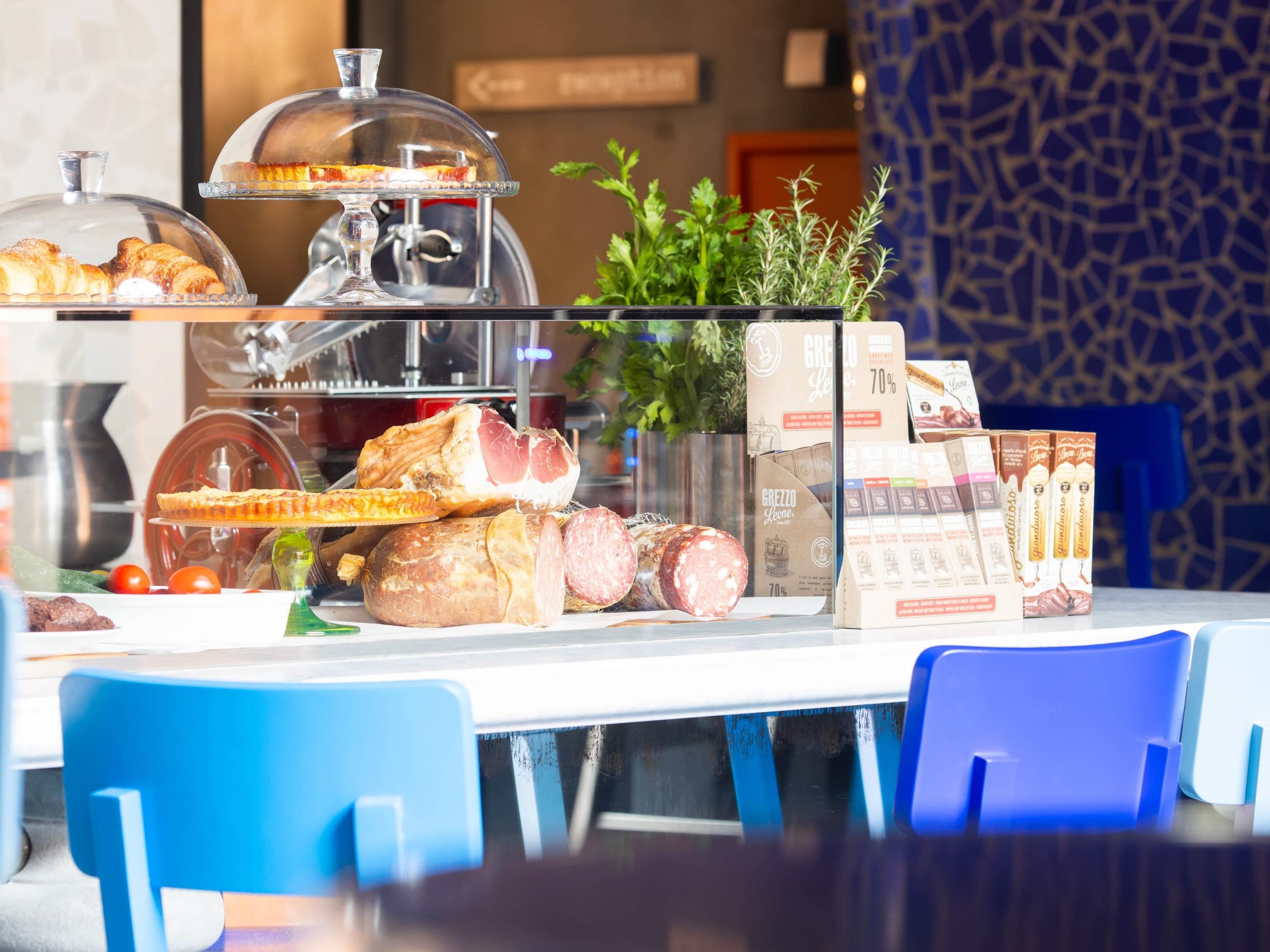 A breakfast buffet with various food items, including pastries, meats, and cheeses, displayed on a glass counter.