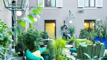 An outdoor seating area with green furniture, potted plants, and a statue.
