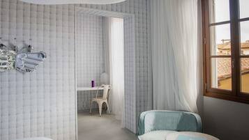 Una stanza con un letto, una scrivania e una sedia. Presente una finestra con tende.