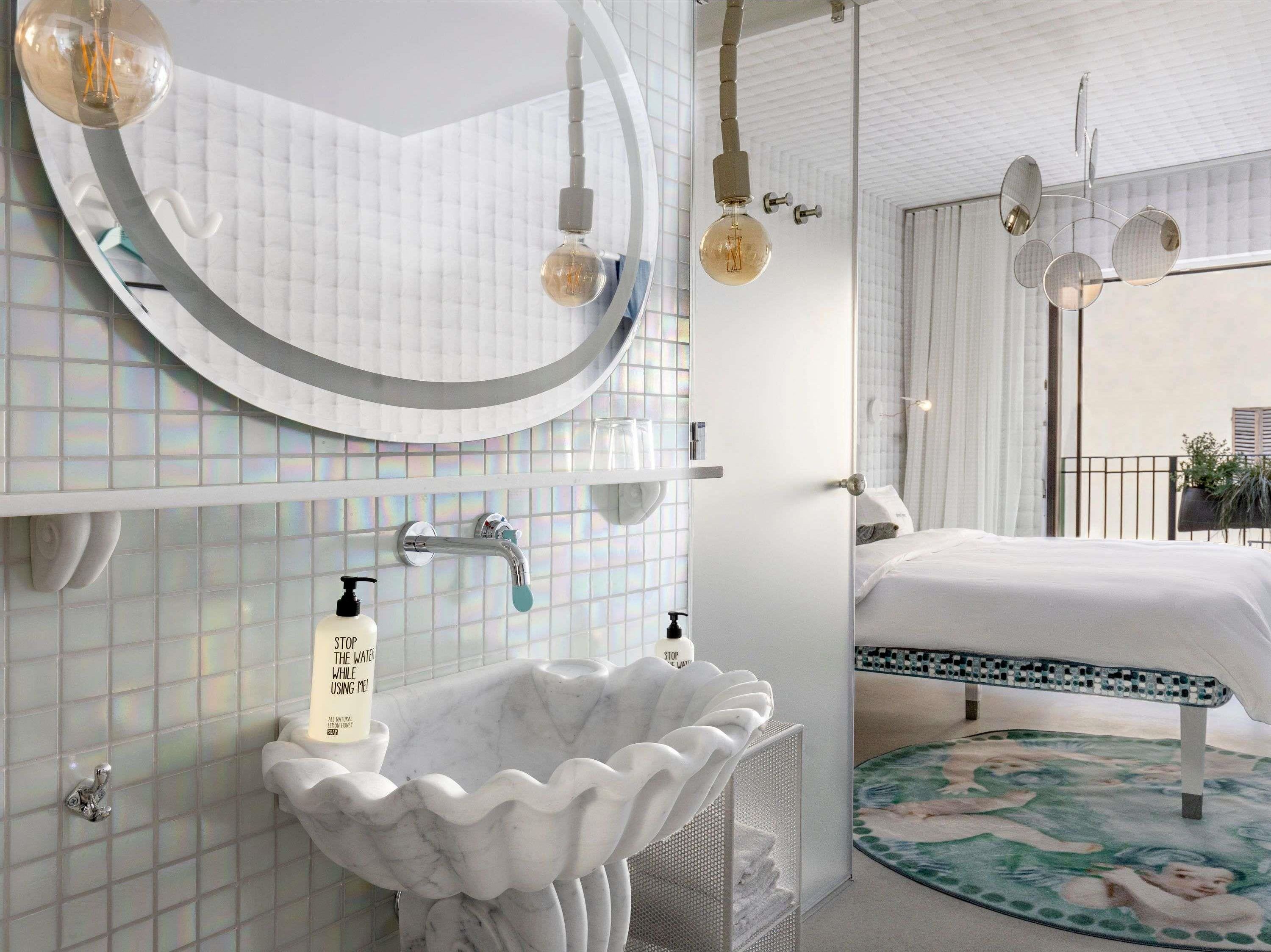 Un baño moderno con lavamanos de mármol, bañera independiente y un espejo grande.
