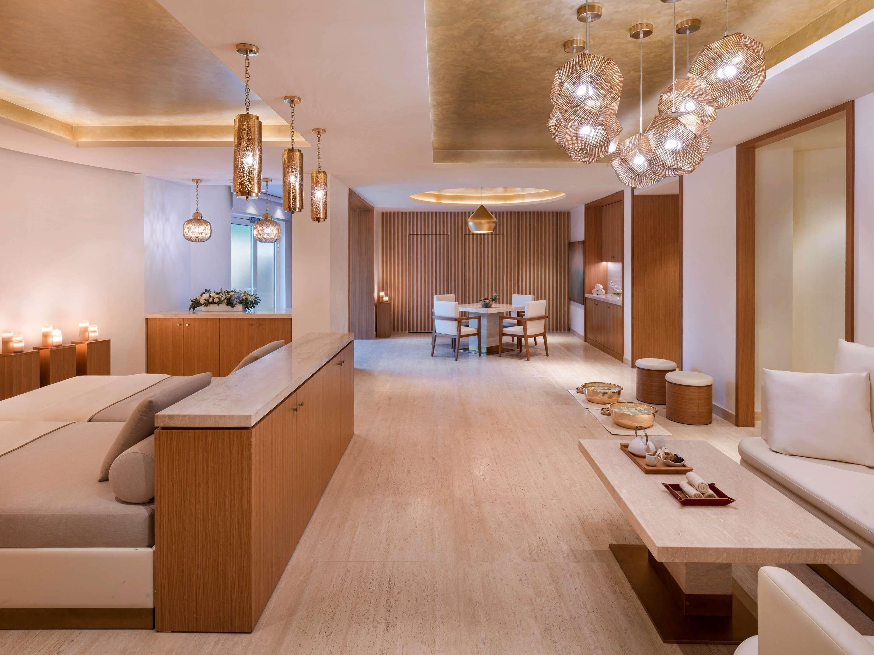 A modern interior with a wooden reception desk, a dining area, and a seating area with a sofa and a table.