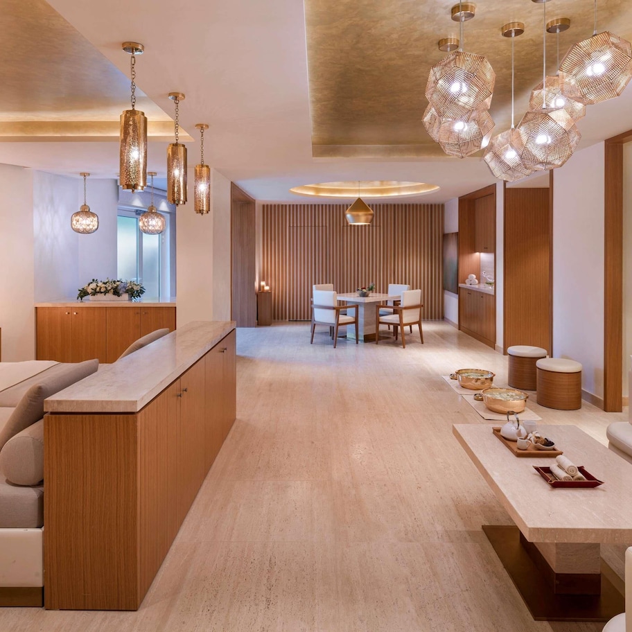 A modern interior with a wooden reception desk, a dining area, and a seating area with a sofa and a table.