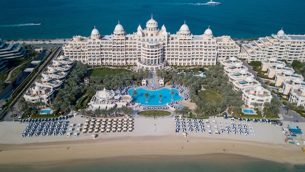 A large resort with a central swimming pool, multiple buildings, and a beach area.