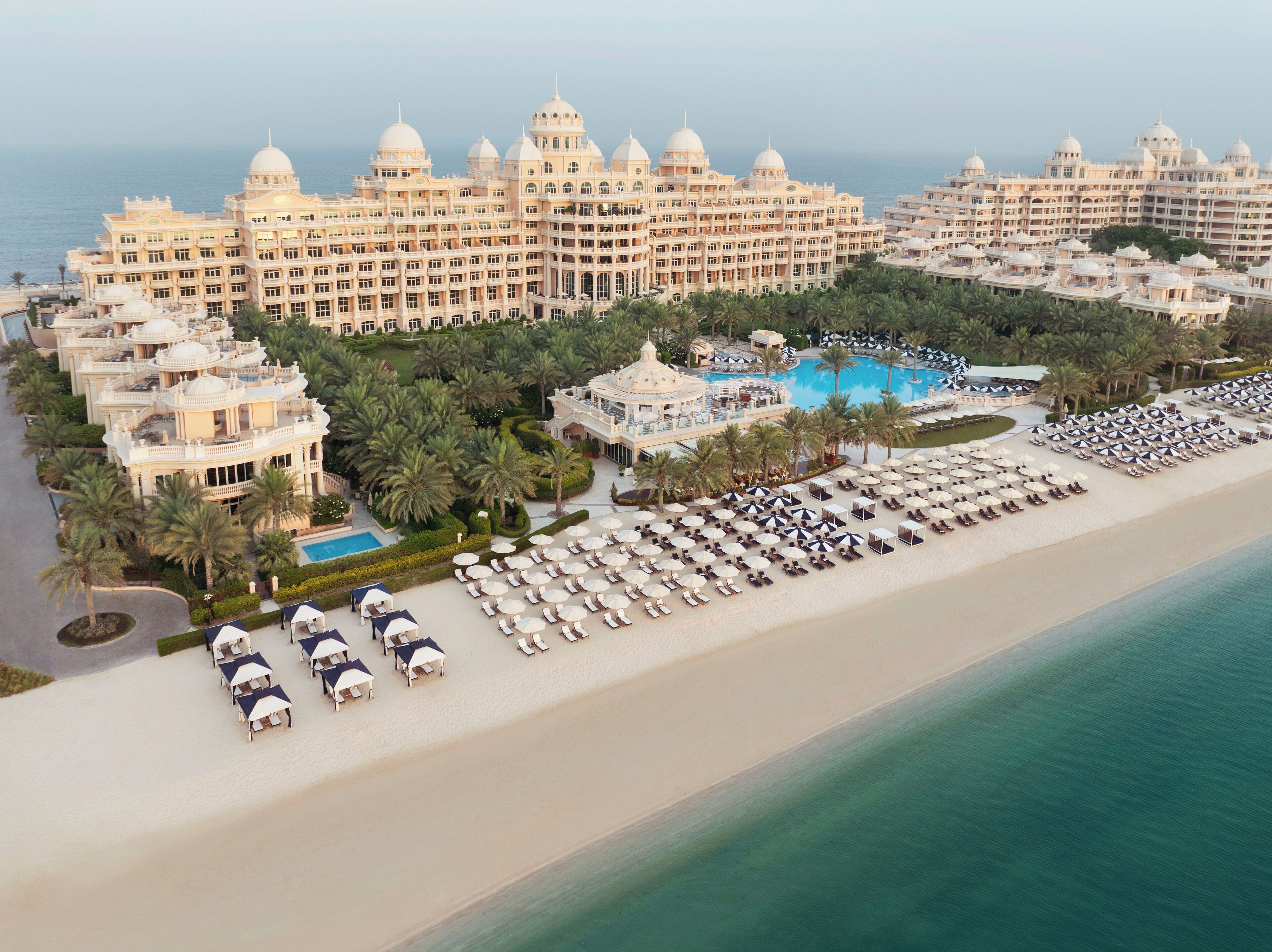 Un gran complejo turístico con varias edificaciones, piscina y playa con tumbonas.