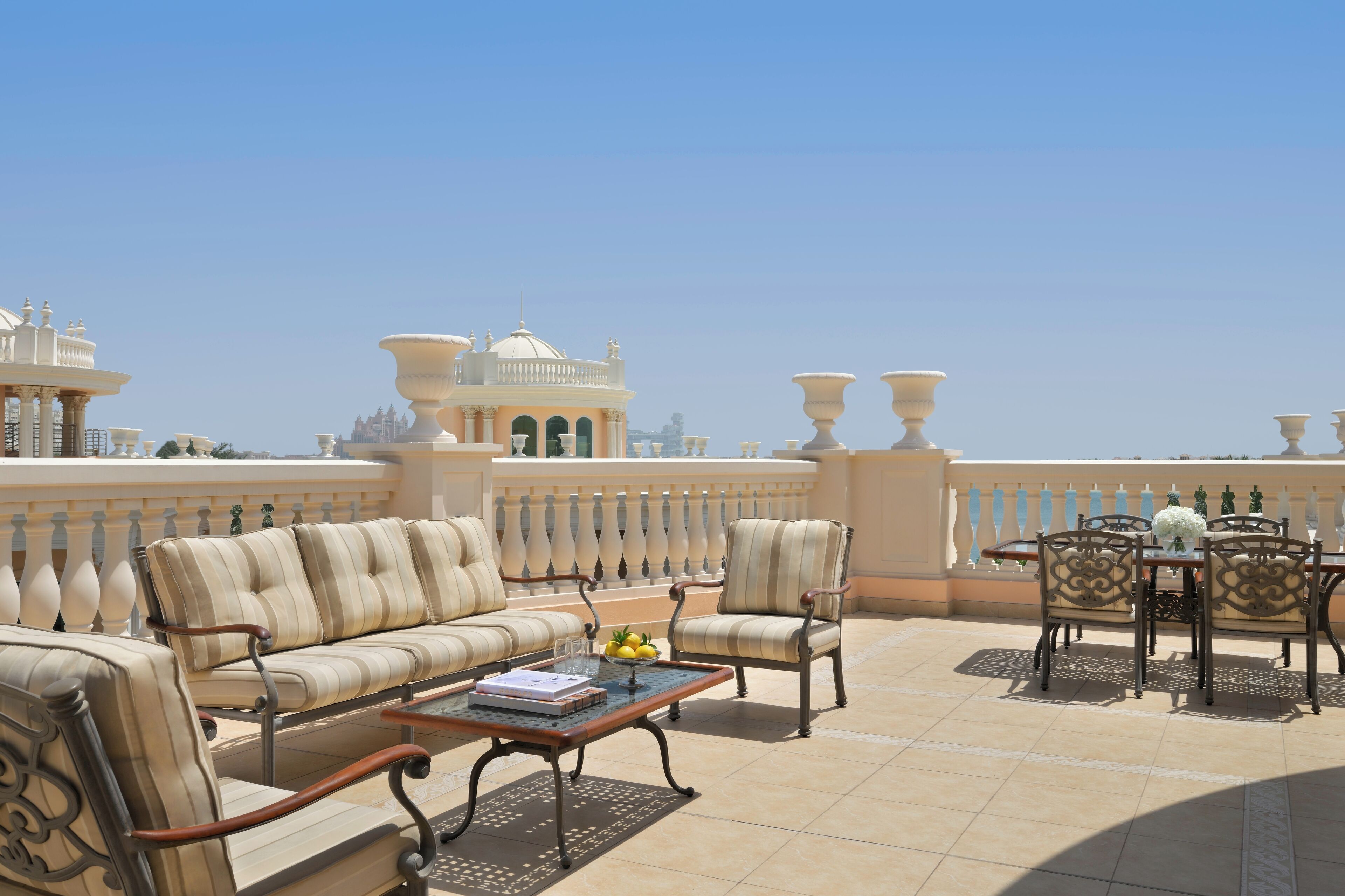 A terrace with a sofa, chairs, a table, and a decorative railing.