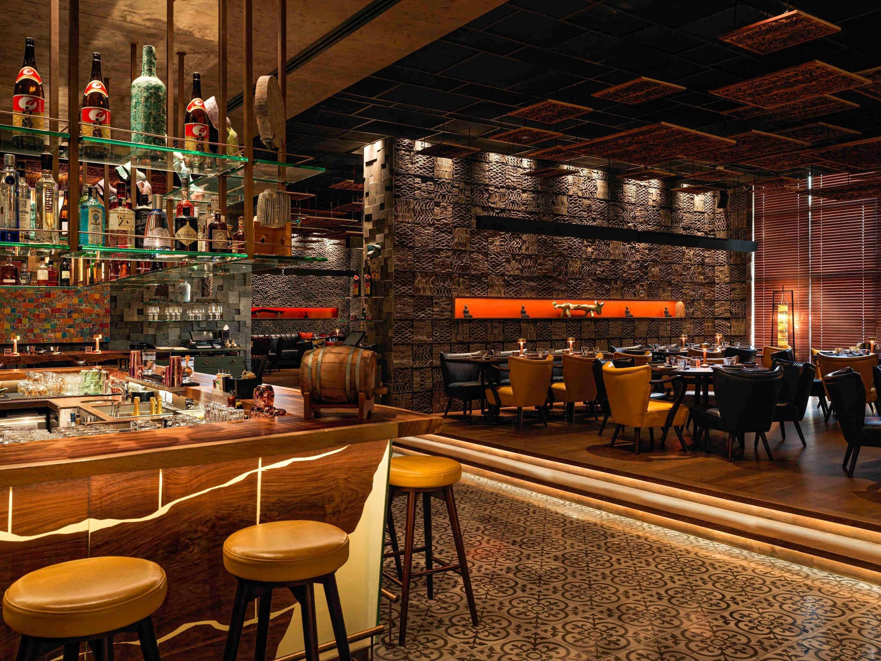 A bar area with stools, a bar counter, and shelves of bottles.