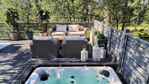A hot tub with a wooden deck, wicker furniture, and potted plants. - Kuukkeli Log Houses Teerenpesä - Premium Suite A48 (Saariselka)