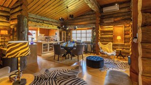 A log cabin interior with a dining area, kitchen, and cozy seating. - Kuukkeli Log Houses Teerenpesä - Premium Suite A48 (Saariselka)