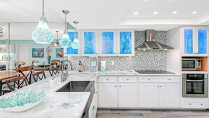 Una cocina moderna con armarios blancos, una isla central e iluminación colgante.
