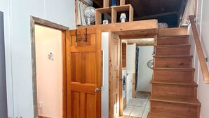 A wooden staircase leading to a second floor, a wooden door, and a laundry area. - True Tiny Home & Community l 4 Mi To Mentone (Mentone)
