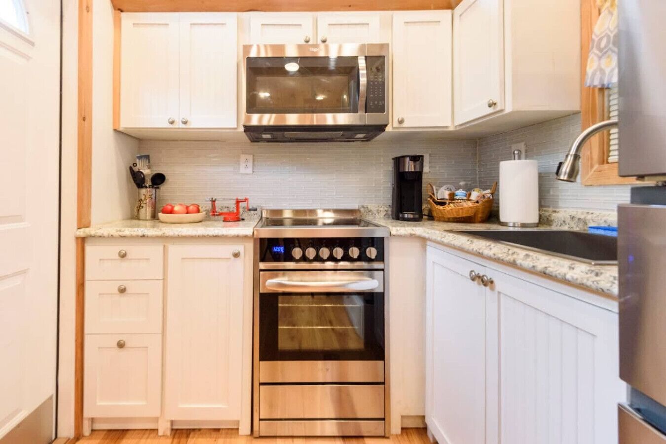 A kitchen with white cabinets, a stainless steel oven, a microwave, and a coffee maker.