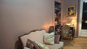 A living room with a sofa, a chair, a bookshelf, and a painting on the wall.