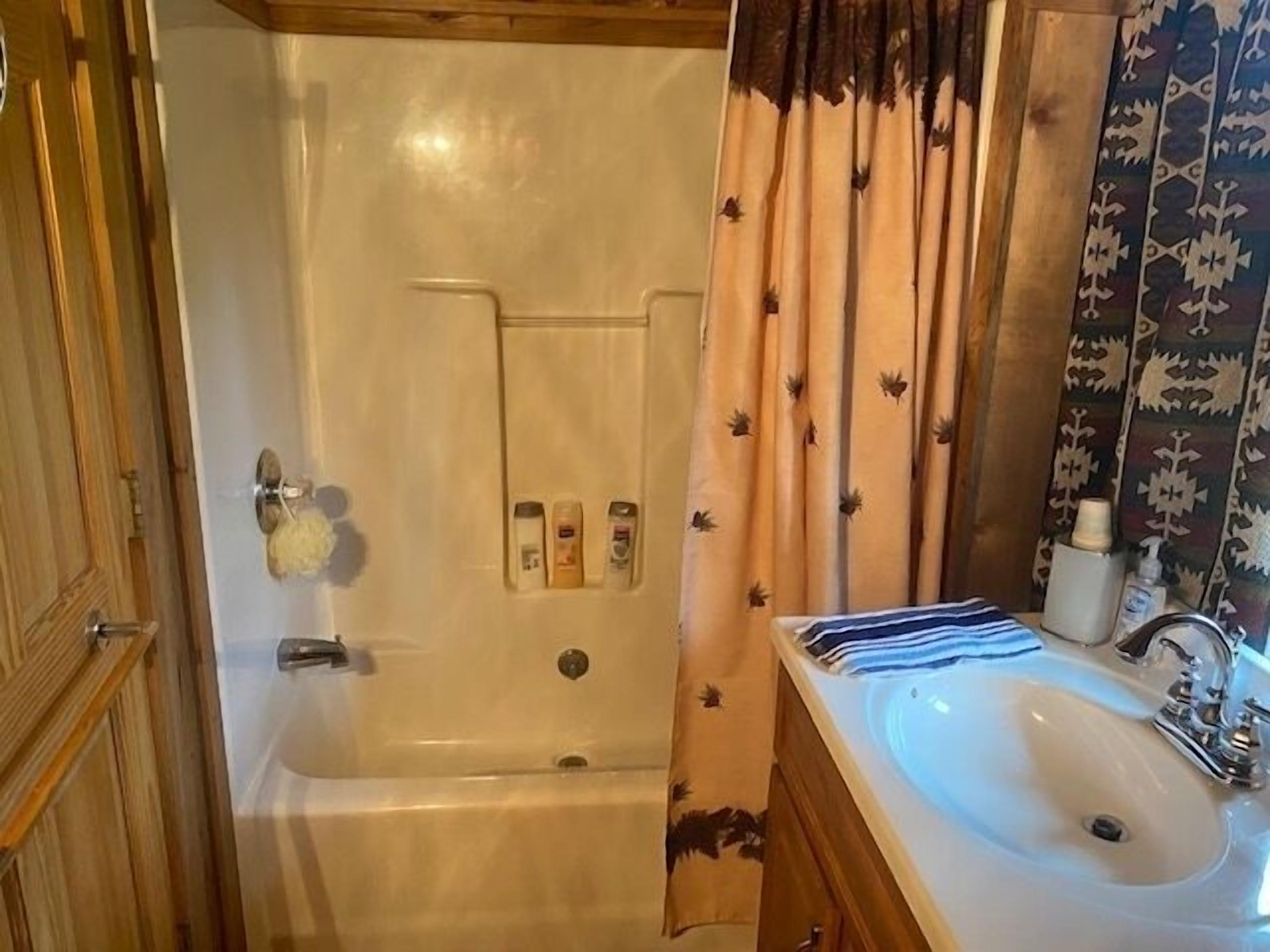 A bathroom with a bathtub, a sink, and a shower curtain.