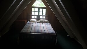 A bedroom with a bed, a window, and a sloped ceiling. - Blue Mountains Jamaican Vacation (St Peters)