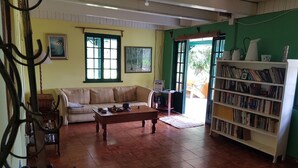 A living room with a sofa, coffee table, and bookshelf. - Blue Mountains Jamaican Vacation (St Peters)
