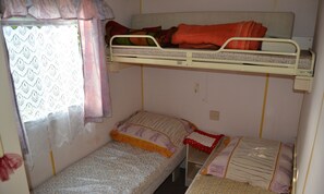 Cozy retreat with a bunk bed and single bed, featuring a window with a lace curtain.
