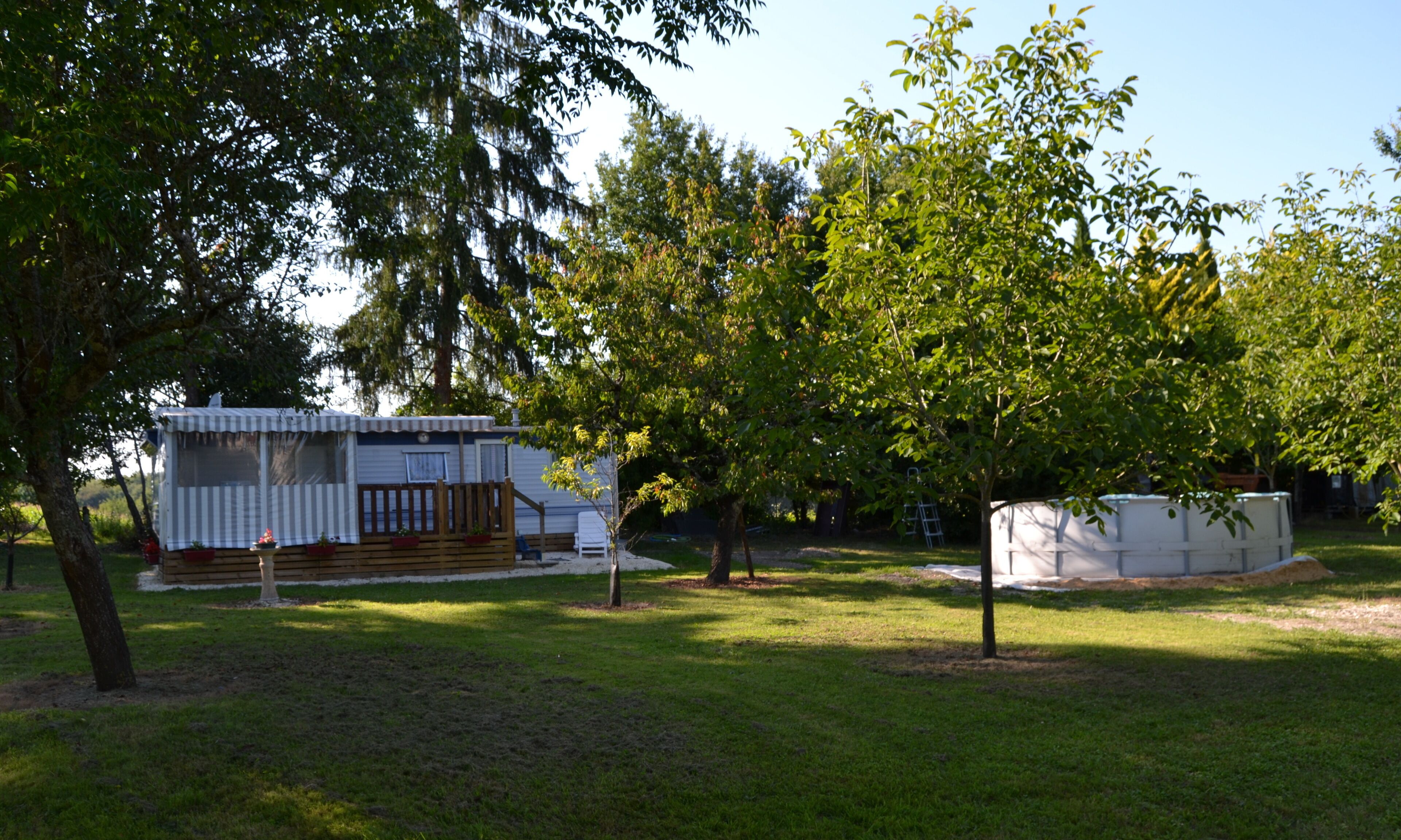 A mobile home with a fenced deck and a small garden area.