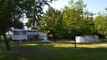A mobile home with a fenced deck and a small garden area.