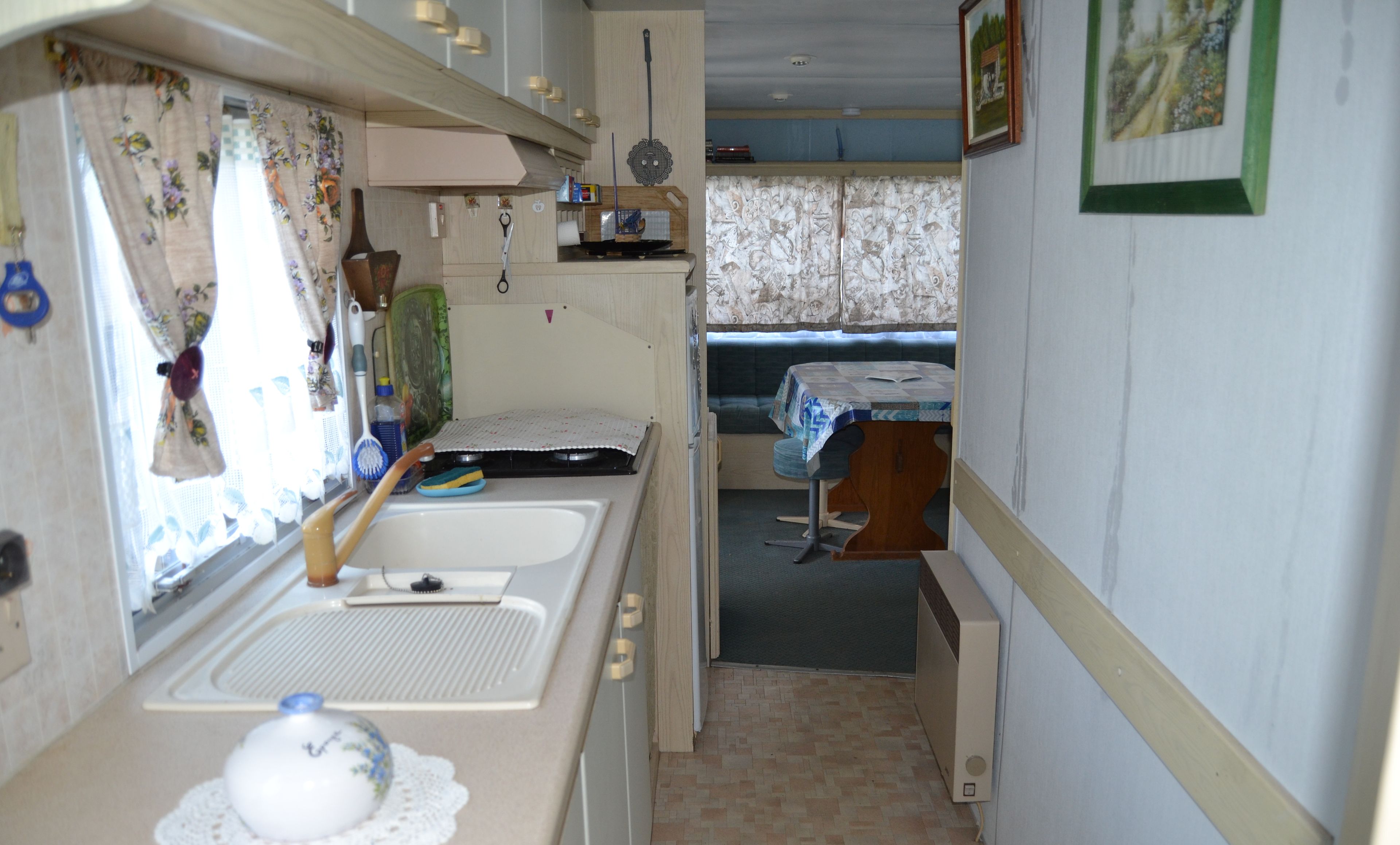 Une cuisine compacte équipée d’un évier, d’une cuisinière et d’un petit coin repas avec une table et des chaises.