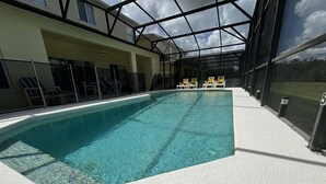 Una piscina interior con agua cristalina, rodeada de sillas de descanso y un techo de vidrio.