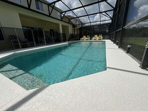 An indoor swimming pool with clear water, surrounded by lounge chairs and a glass ceiling.