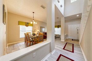 A dining area with a table, chairs, and a hanging light fixture.