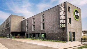 Un moderno edificio de hotel con área de recepción, múltiples ventanales y un llamativo letrero de B&B Hotels.