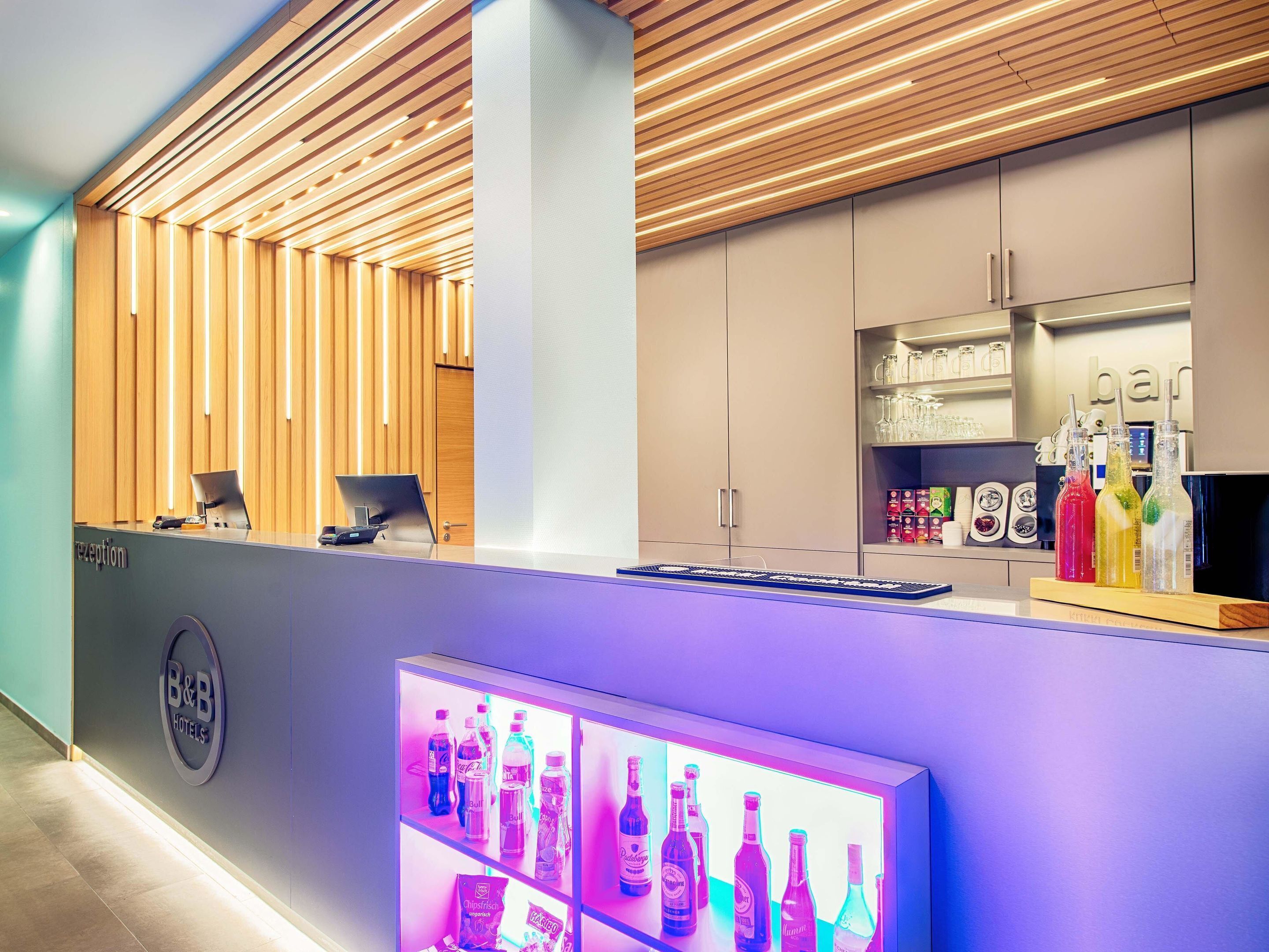 A reception desk with a computer, a glass display case with bottled beverages, and a wooden panel wall.