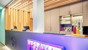 Un mostrador de recepción con una computadora, una vitrina de vidrio con bebidas embotelladas y un panel de pared de madera.