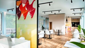 Un espacio de oficina moderno con mobiliario blanco, suelo de madera y ventanas amplias.