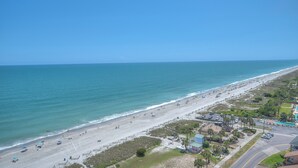 A beach with a road, buildings, and a clear sky.