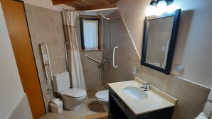 Un baño pequeño con ducha, inodoro y lavamanos.
