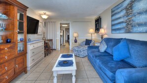 A living room with a blue sofa, a white coffee table, a wooden cabinet, and a painting on the wall. - Boardwalk Beach Resort #932 Gorgeous1 Bedroom Oceanfront Condo (Myrtle Beach)