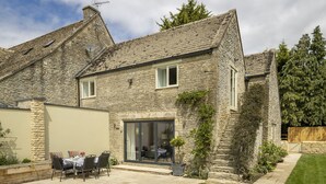 A stone house with a patio, a sliding glass door, and a small garden. - Cats Abbey Cottage a charming,  Northleach , Gloucestershire (Northleach)