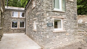 A stone building with a sign indicating 'Norton' and a directional arrow. - Norton (Keswick)