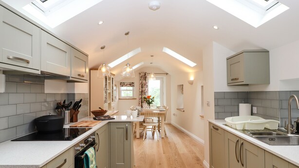 A modern kitchen with skylights, a central island, and a dining area. - Norton (Keswick)