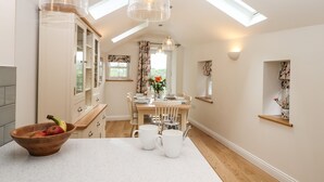 A modern kitchen with a wooden table, two white mugs, and a bowl of fruit. - Norton (Keswick)