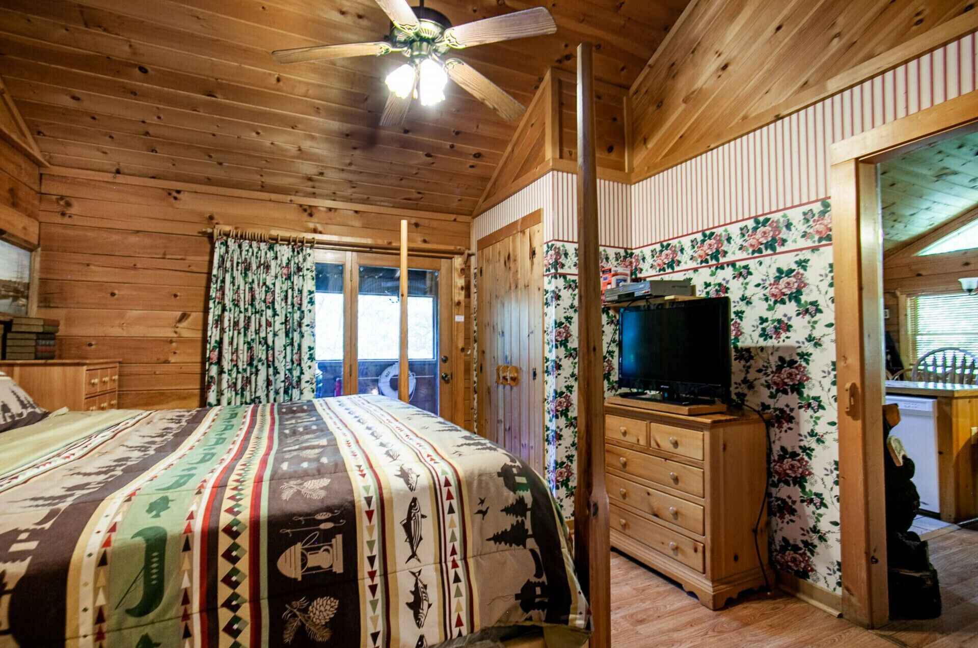 Una camera in una baita di legno con un letto, una televisione e un comò di legno.