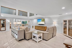 A spacious living area with a sectional sofa, a coffee table, and a TV mounted on the wall. - Luxury Pool and Rooftop Deck, Walk to Siesta Key Beach and Village! - Casa Siest (Siesta Key)