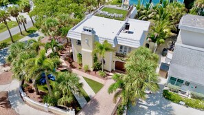 A two-story building with a flat roof, surrounded by palm trees and a paved driveway. - Luxury Pool and Rooftop Deck, Walk to Siesta Key Beach and Village! - Casa Siest (Siesta Key)