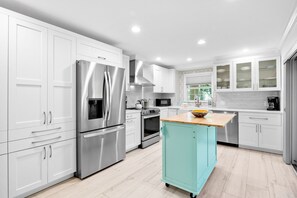 A modern kitchen with stainless steel appliances, white cabinetry, and a teal island. - Luxury Pool and Rooftop Deck, Walk to Siesta Key Beach and Village! - Casa Siest (Siesta Key)