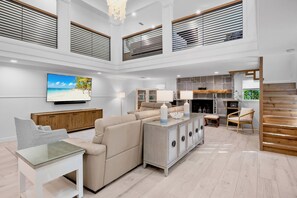 A spacious living area with a sofa, a glass coffee table, and a television mounted on the wall. - Luxury Pool and Rooftop Deck, Walk to Siesta Key Beach and Village! - Casa Siest (Siesta Key)