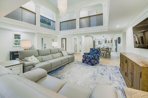 Un salón amplio con un sofá grande, un sillón estampado y un aparador de madera.
