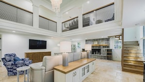 A spacious living area with a large sectional sofa, a small round table, and a built-in kitchen area with a stone fireplace. - Luxury Pool and Rooftop Deck, Walk to Siesta Key Beach and Village! - Casa Siest (Siesta Key)