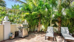 An outdoor patio with a barbecue grill, a gas cylinder, and two lounge chairs. - Luxury Pool and Rooftop Deck, Walk to Siesta Key Beach and Village! - Casa Siest (Siesta Key)
