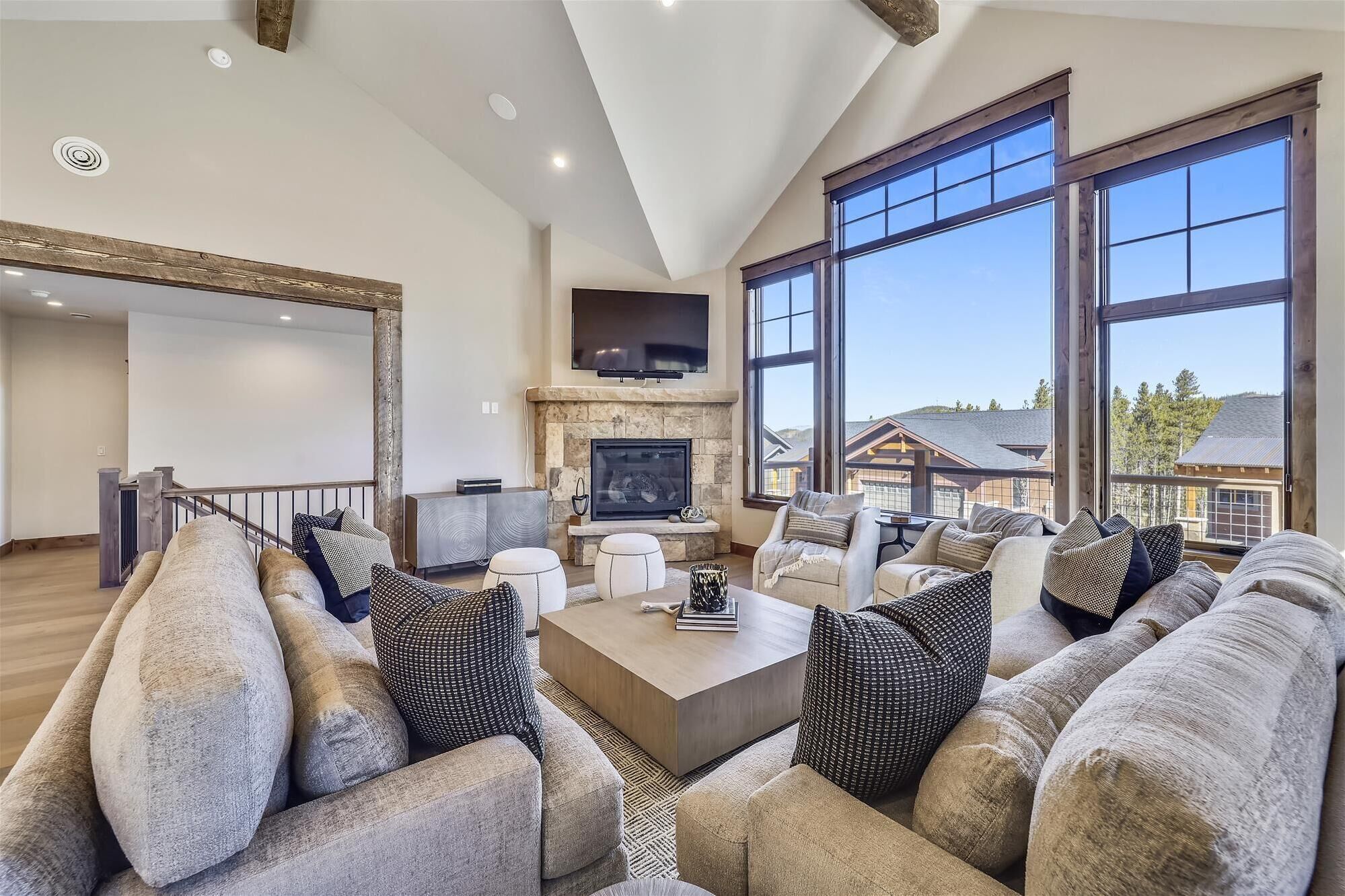 A spacious living room with a fireplace, large windows, and a modern fireplace mantel.