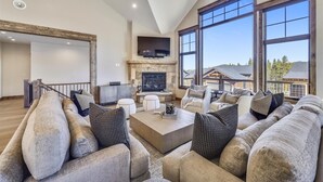 A spacious living room with a fireplace, large windows, and a modern fireplace mantel. - Cocoa Cabin: New Baldy Mtn Home, Hot Tub & Steam Shower, EV Charger! (Breckenridge)