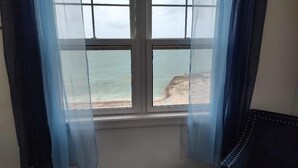 Ett rum med ett stort fönster med utsikt över en strand.