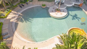 Vista aérea de una piscina con diseño circular, rodeada de sillones de descanso y una palmera.